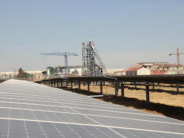 In the foreground, there are several PV systems. In the background are the production facilities of the mine.